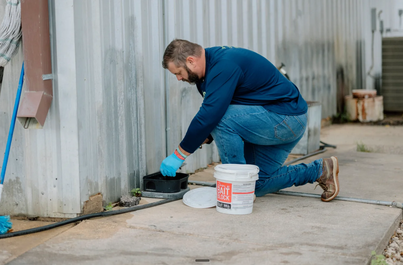 Jason placing a rodent bait station at a commercial property in Brazos Valley.